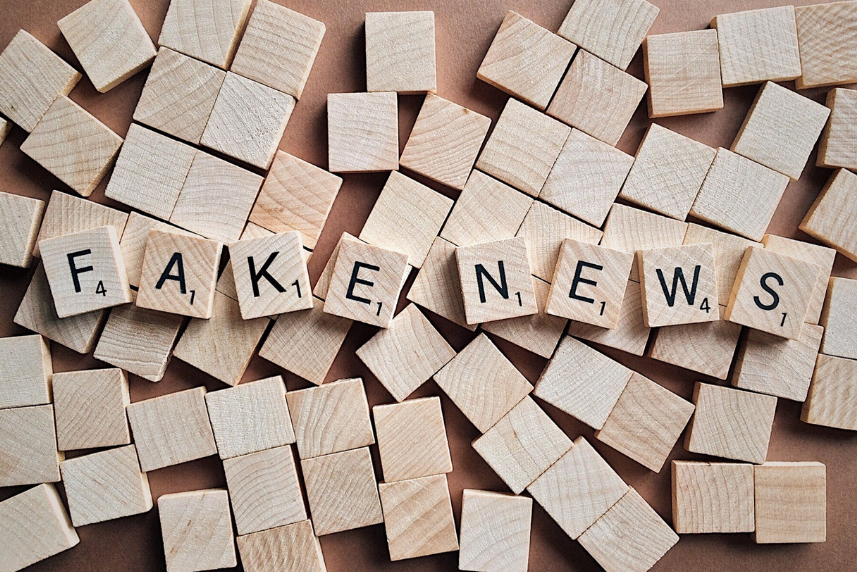 Buchstaben des Scrabble-Spieles auf Holzplättchen zusammengelegt zu Fake News. Verschwörungsideologien, Verschwörungstheorien, Verschwörungserzählungen - Canva
