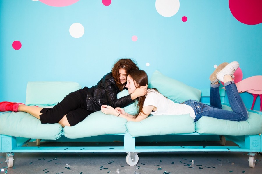 Zwei Freundinnen auf einem Sofa umarmen sich und lachen, auf dem Boden liegt Konfetti. Lebenslagen, Feiern, Umzug, Jugendliche, - Pixabay
