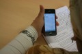 Handy (iPhone) in der Hand am Schreibtisch bei der Arbeit. - Quelle/Autor: Michael Dawid