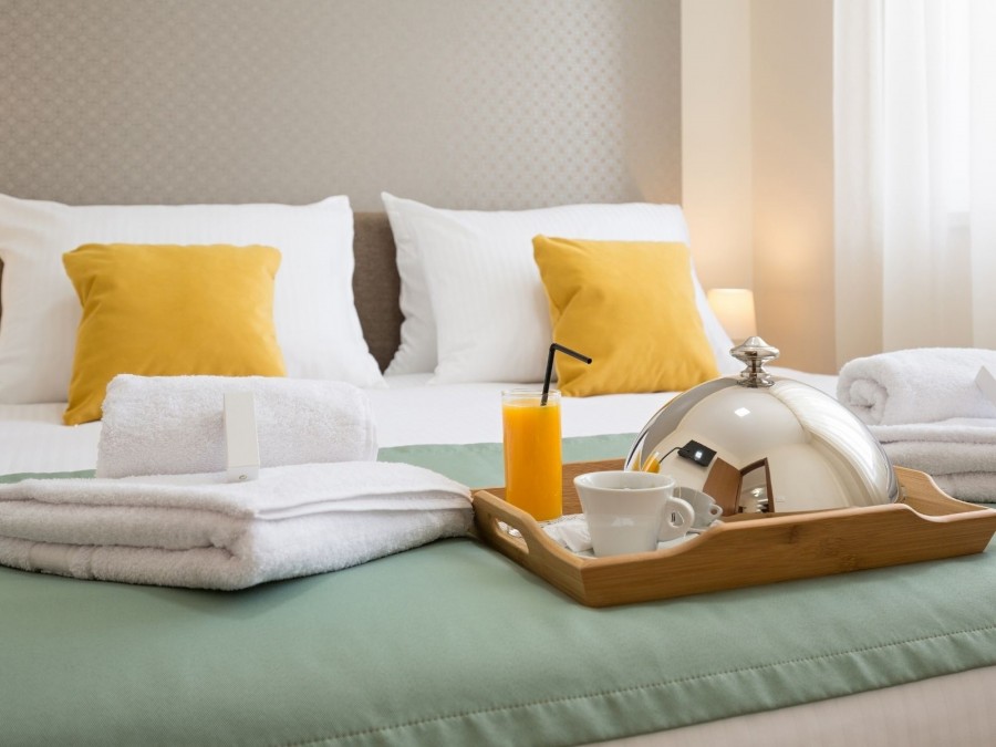 Gefülltes Frühstückstablett auf einem Bett eines Hotels. Übernachtungsmöglichkeiten, Unterkunft - Canva