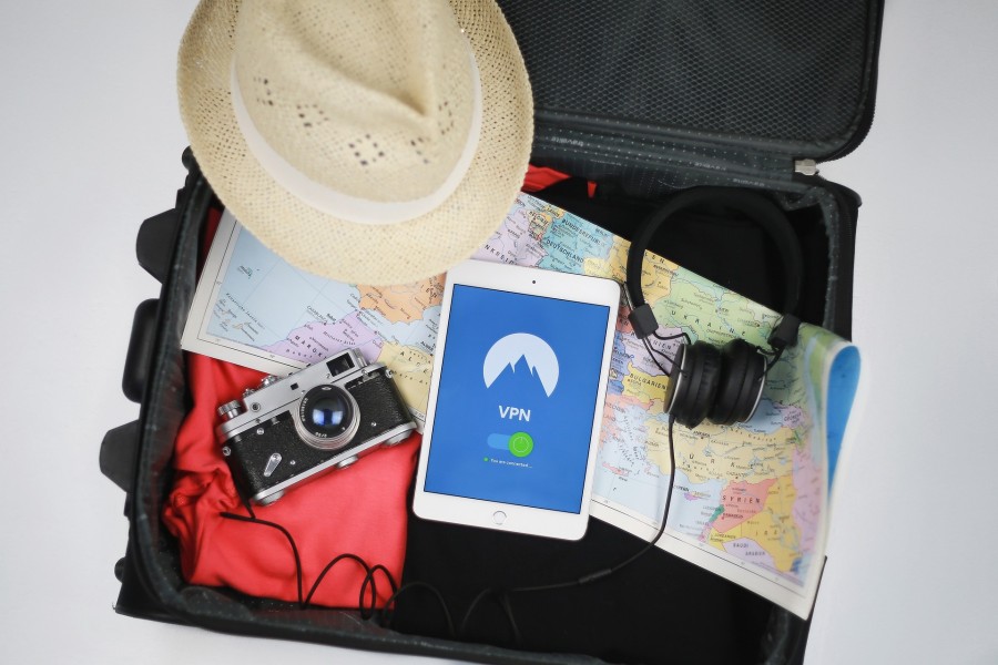 Wichtige Informationen für Reiserückkehrende: Das Foto zeigt einen offenen Koffer mit einer Weltkarte, einem Fotoapparat, einem Hut, einem Handy und einer roten Jacke - Stefan Coders auf Pixabay