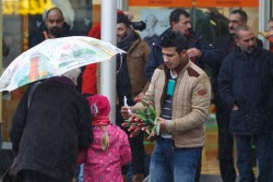 Flüchtlinge setzen Zeichen und suchen den Dialog: Bewohner der Flüchtlingsunterkunft auf dem Kirmesplatz an der Mintarder Straße verteilen Blumen vor dem Mülheimer Forum