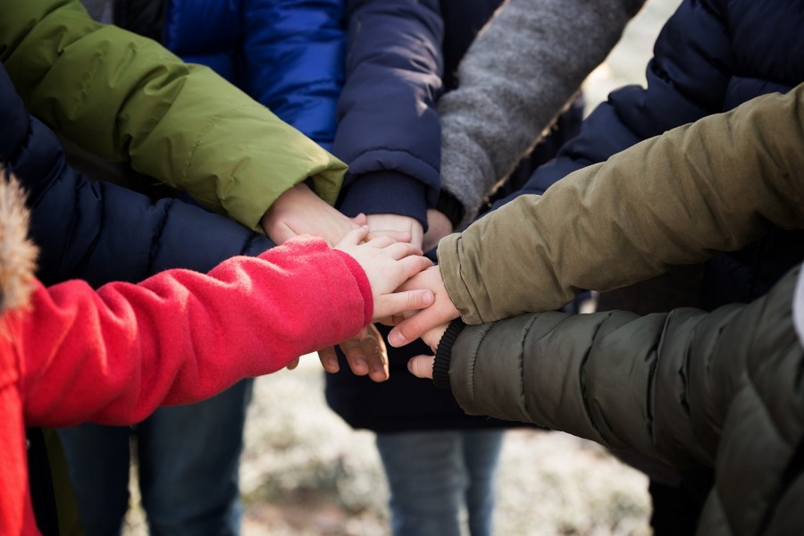 Hände vieler Menschen in bunten Winterjacken schließen sich zusammen. Inklusion, Integration, Herkunft, Bildungsstand, Ungleichheiten, Zusammenhalt, Team - Bild von Marta Reinartz auf Pixabay