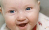 Bild eines kleinen lachenden Babys das auf einer Decke liegt. - Elternzeitbroschüre der Stadt Mülheim