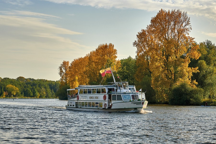 Weiße Flotte im Herbst: Ein Schiff der Weißen Flotte fährt auf der Ruhr, im Hintergrund herbstliche Natur mit rot-gelb gefärbten Blättern an den Bäumen - Achim Meurer Copyright MST