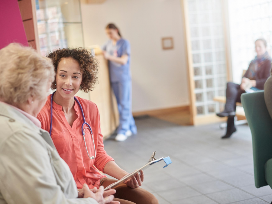 Frau im Gespräch mit einer jungen Ärztin in einem Wartezimmer einer großen Praxis. - canva.com