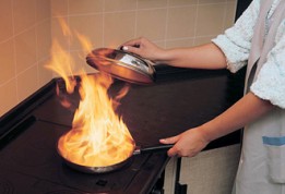 Ein Koch flambiert in einer Pfanne. Brandschutztips zur Vermeidung von Bränden im Haushalt. 
