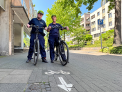 Das Ordnungsamt Mülheim hat eine Fahrradstaffel eingerichtet. Zwei Mitarbeitende mit gelben Fahrradhelmen und blauer Dienstkleidung haben mit ihren Dienst-E-Bikes auf dem Fahrradweg an der Delle angehalten. 