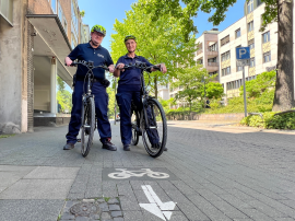 Das Ordnungsamt Mülheim hat eine Fahrradstaffel eingerichtet. Zwei Mitarbeitende mit gelben Fahrradhelmen und blauer Dienstkleidung haben mit ihren Dienst-E-Bikes auf dem Fahrradweg an der Delle angehalten.  - Quelle/Autor: Sarah Sternol, Onlineteam