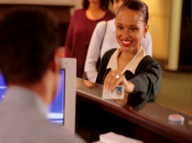 Lächelnde Frau zeigt einem Mitarbeiter in der Ausländerbehörde ihren Ausweis. Staatsbürgerschaft, Aufenthaltstitel, Ausländeramt