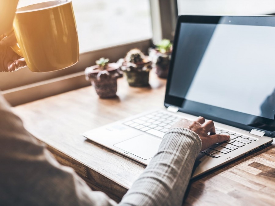 Person an einem Tisch führt eine Tasse zum Mund, auf dem Tisch steht ein Laptop, eine Hand ist an der Tastatur. Prüfen Sie den Status des gewünschten Dokumentes online. - Canva Person an einem Tisch führt eine Tasse zum Mund, auf dem Tisch steht ein Laptop, eine Hand ist an der Tastatur. Symbol für Homeoffice, Heimzugriff - Canva