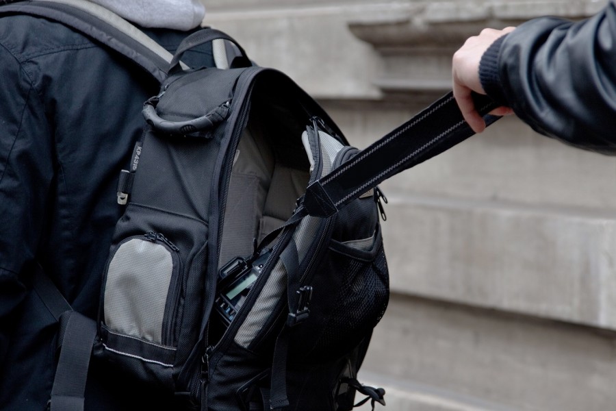 Person stiehlt einer anderen Person eine Kamera aus einem Rucksack, Trickdiebe, Betrüger, Diebstahl - Bild von Ganossi auf Pixabay