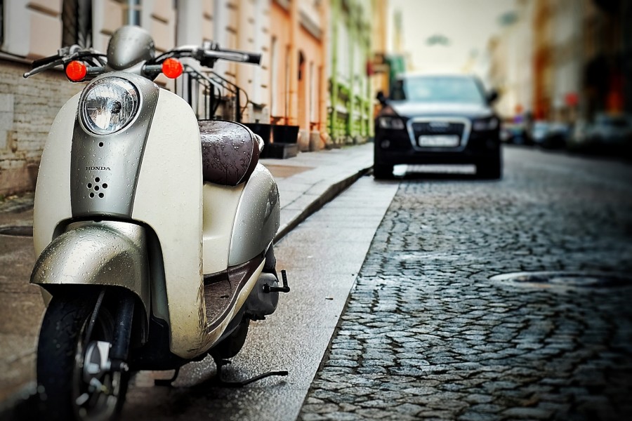 Das Foto zeigt einen Motorroller und ein Auto geparkt in einer Straße mit Kopfsteinpflaster und Altbauten. Autos, Motorrad, Motorräder, Parken, Kraftfahrzeuge - Pixabay