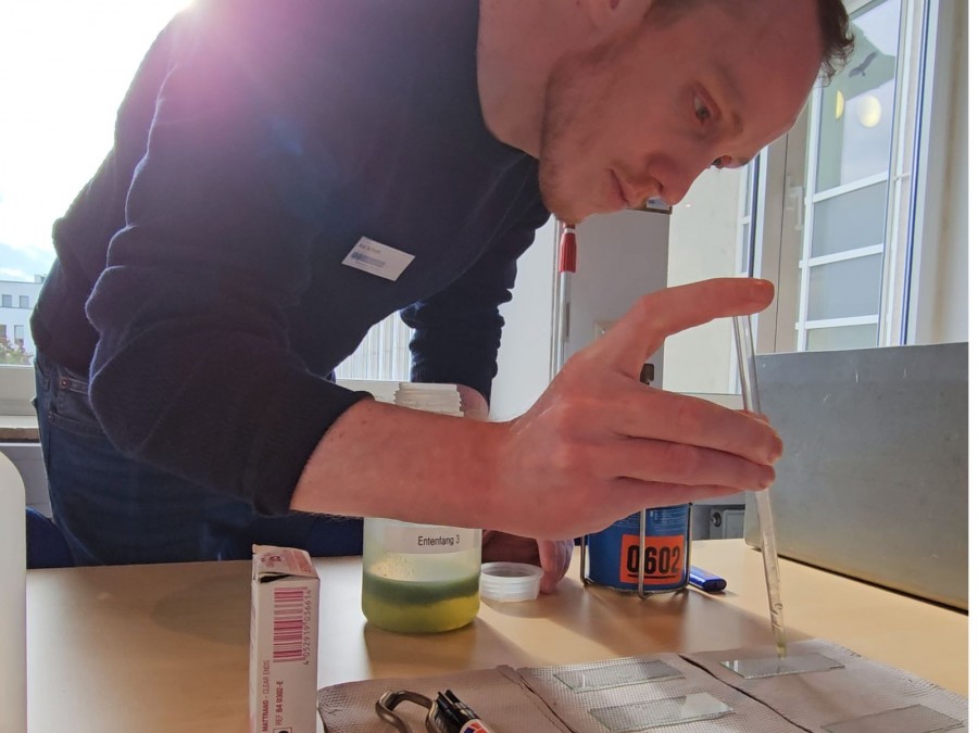 Auf dem Foto ist ein Gesundheitsingenieur. Er pippetiert eine Wasserprobe auf einen Objektträger. - Gesundheitsamt - F. Fedtke