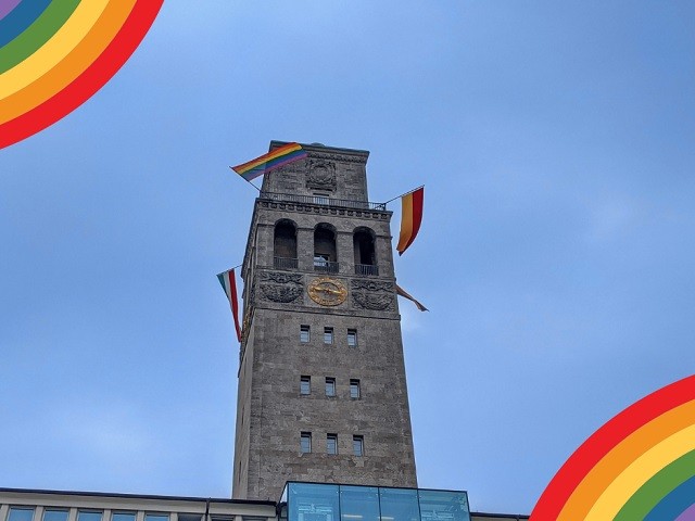Auf dem Foto ist der Rathausturm mit einer Regenbogenflagge. - Onlineteam
