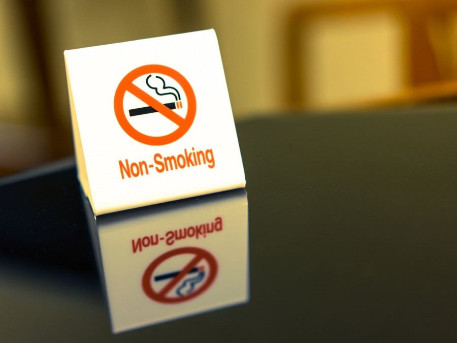 Schild mit durchgestrichener Zigarette und Non-Smoking auf einem Tisch. Rauchen nicht erlaubt, Rauchverbot. - Canva