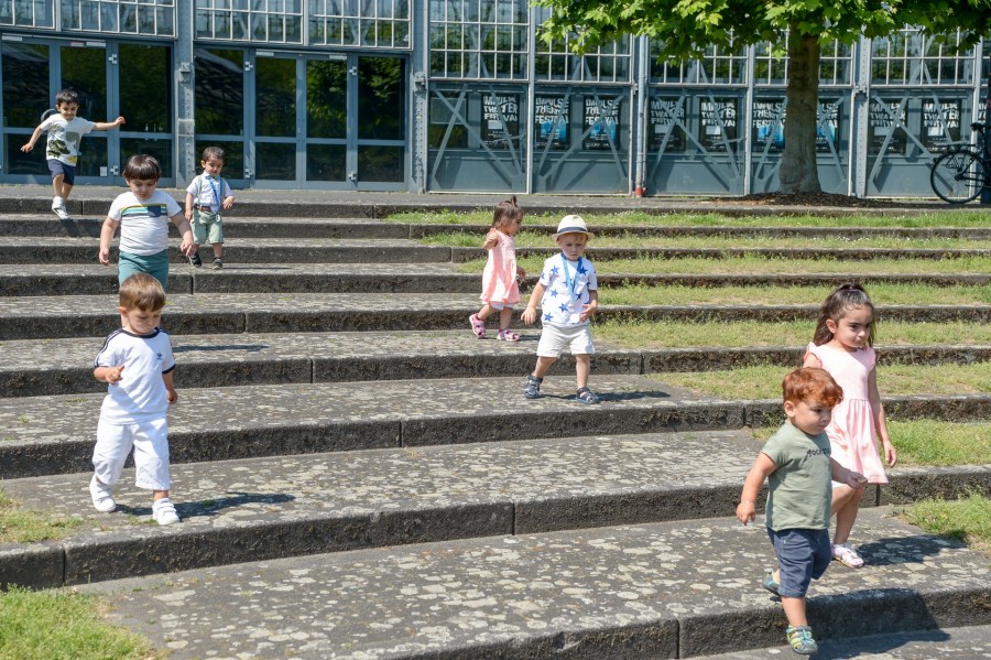 Opstapje-Familien beim Abschiedsfest 2020 in der MüGa (Mülheims Garten an der Ruhr). Das Foto zeigt kleine Kinder die an der Drehscheibe am Ringlokschuppen die Rasenstufen runterlaufen. - Walter Schernstein