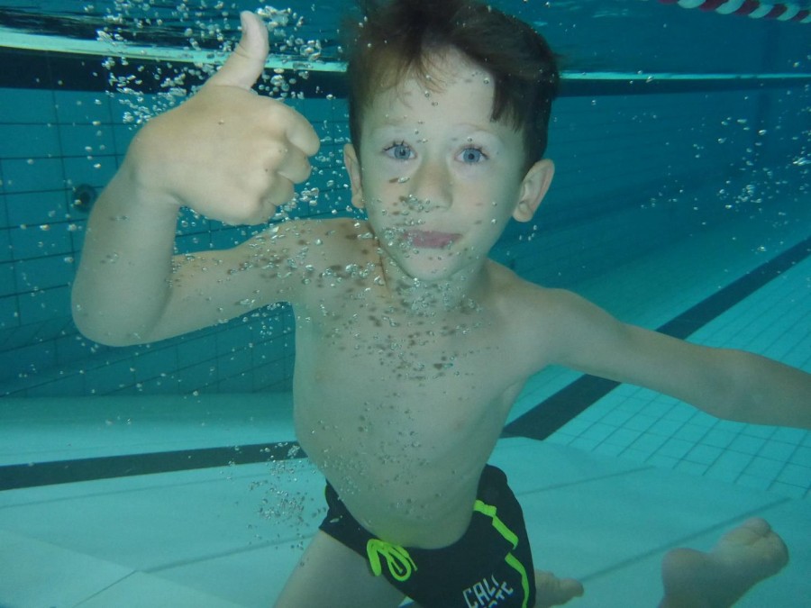 Foto vom Sommer-Schwimmcamp der Deutschen Lebensrettungsgesellschaft (DLRG) Müheim. Das Bild zeigt einen Jungen in einem Schwimmbecken unter Wasser, der seinen rechten Daumen in Höhe streckt. - DLRG Mülheim