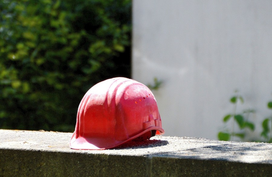 Bauarbeiterhelm vor einer Baustelle. Neubau, Umbau, Umlegung, Bebauungsplan - Pixabay