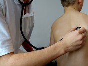 Kinderarzt hört mit einem Stethoskop die Atmung am Rücken eines Kindes ab. Gesundheit, ärztliche Untersuchung