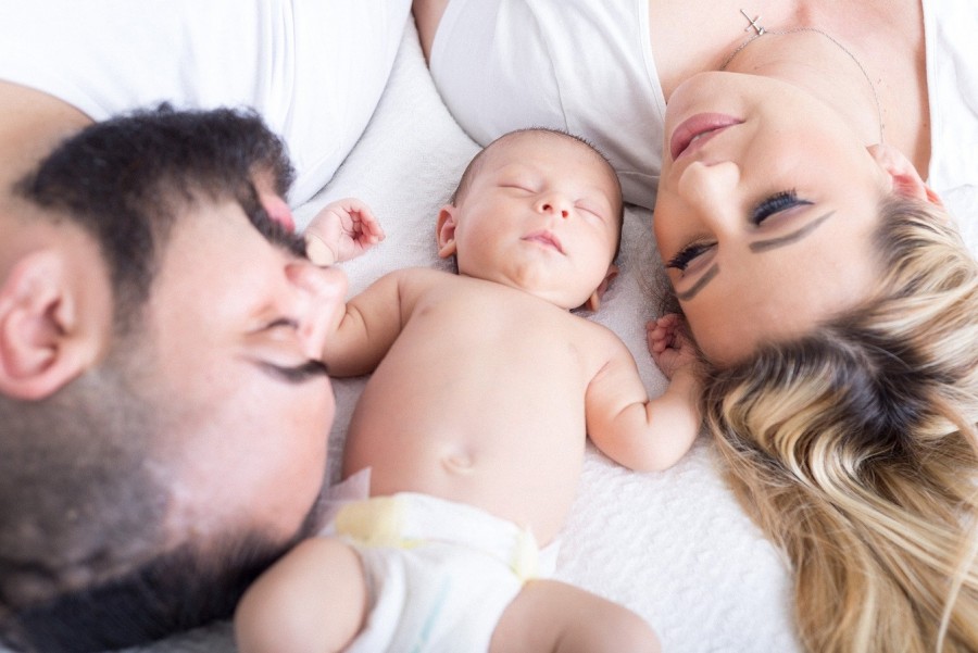 Ein neugeborenes Baby liegt zwischen den Eltern auf dem Bett. Familie, Geburt, Nachwuchs - Bild von Stephanie Pratt auf Pixabay