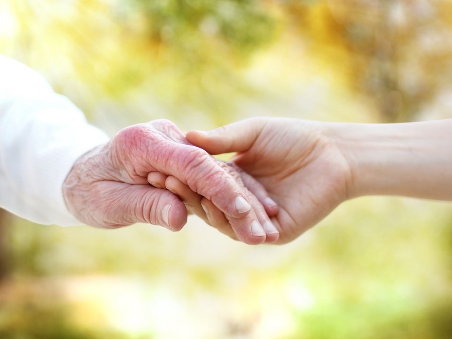 Hände einer jungen und einer alten Person halten sich fest. Senioren, Seniorinnen, Altenpflege - Canva