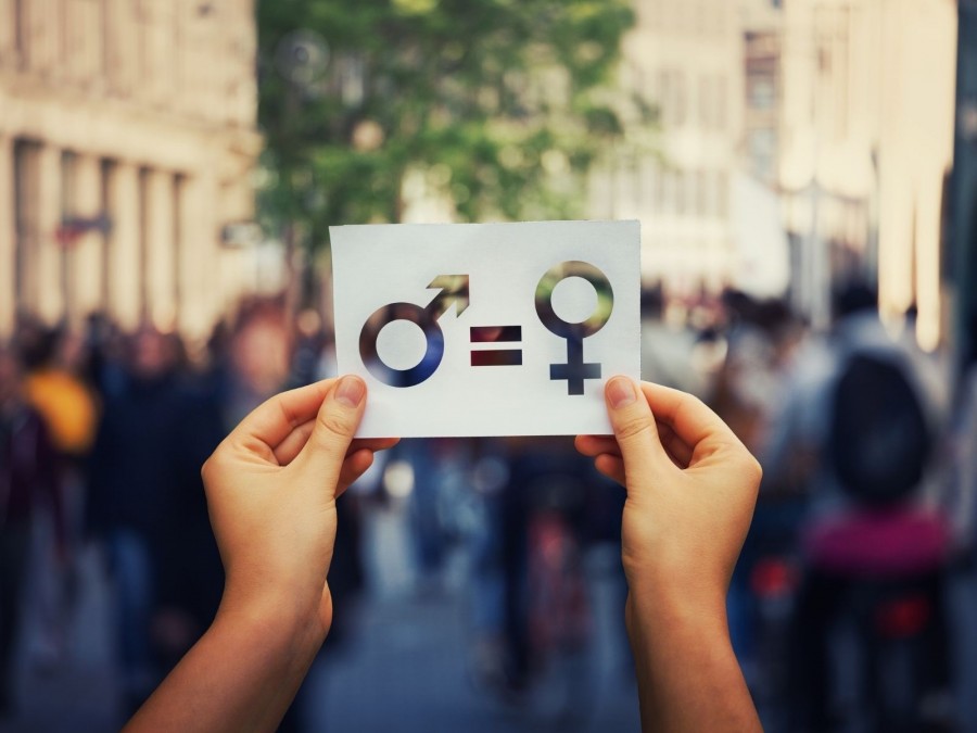 Hände halten ein Schild hoch auf dem das Symbol für Frauen und Männer mit einem Gleichzeichen. Gleichstellung von Frauen und Männern. Gleichstellungsstelle - Canva