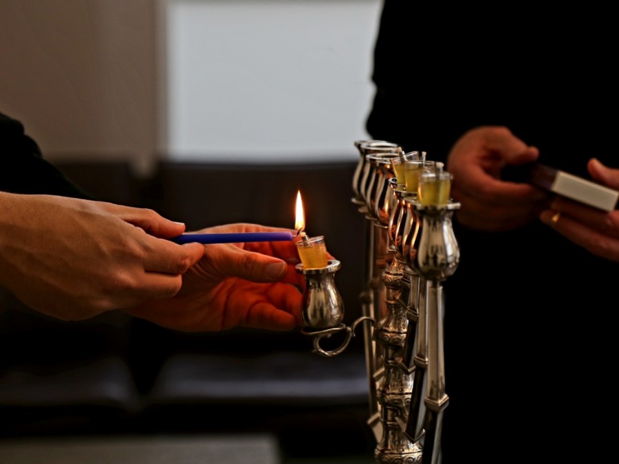 Auf ist ein Chanukkaleuchter im Bürgermeisterzimmer abgebildet, der von Rabbiner David Geballe und Bürgermeister Markus Püll angezündet wird. Man sieht nur ihre Hände. - Jasmin Kramer