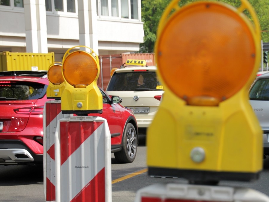 Baustellen und Absperrungen, wie hier auf dem Dickwall, führen zu Verkehrsbehinderungen im Stadtgebiet. Das Foto zeigt kleine Absperrbarken mit gelb/orangen Leuchten hintereinander sowie Autos und ein Gebäude im Hintergrund. - Sabine Meier