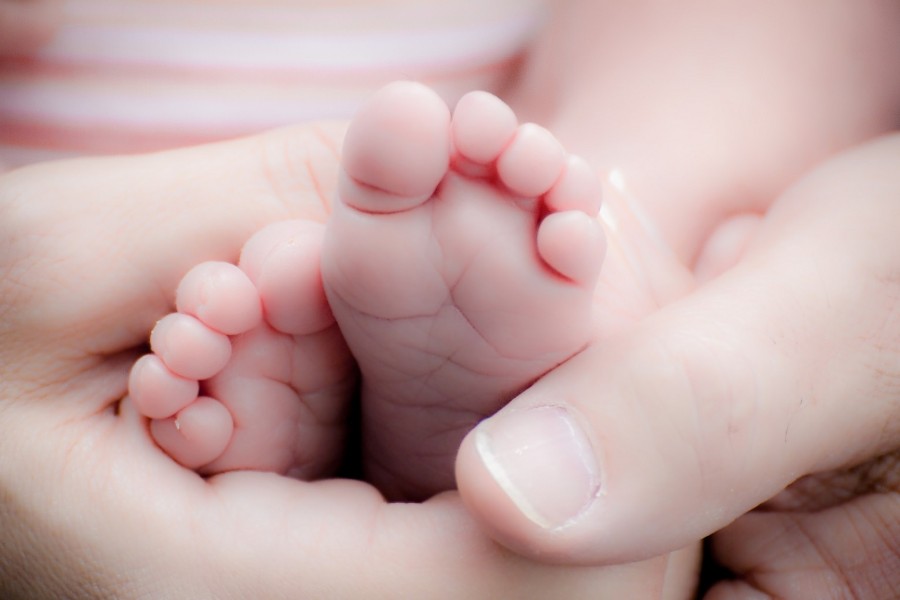 Hände halten die kleinen Füße eines neu geborenen Babys in die Kamera. Geburten, Adoption, Familienzuwachs - Bild von sherwood auf Pixabay