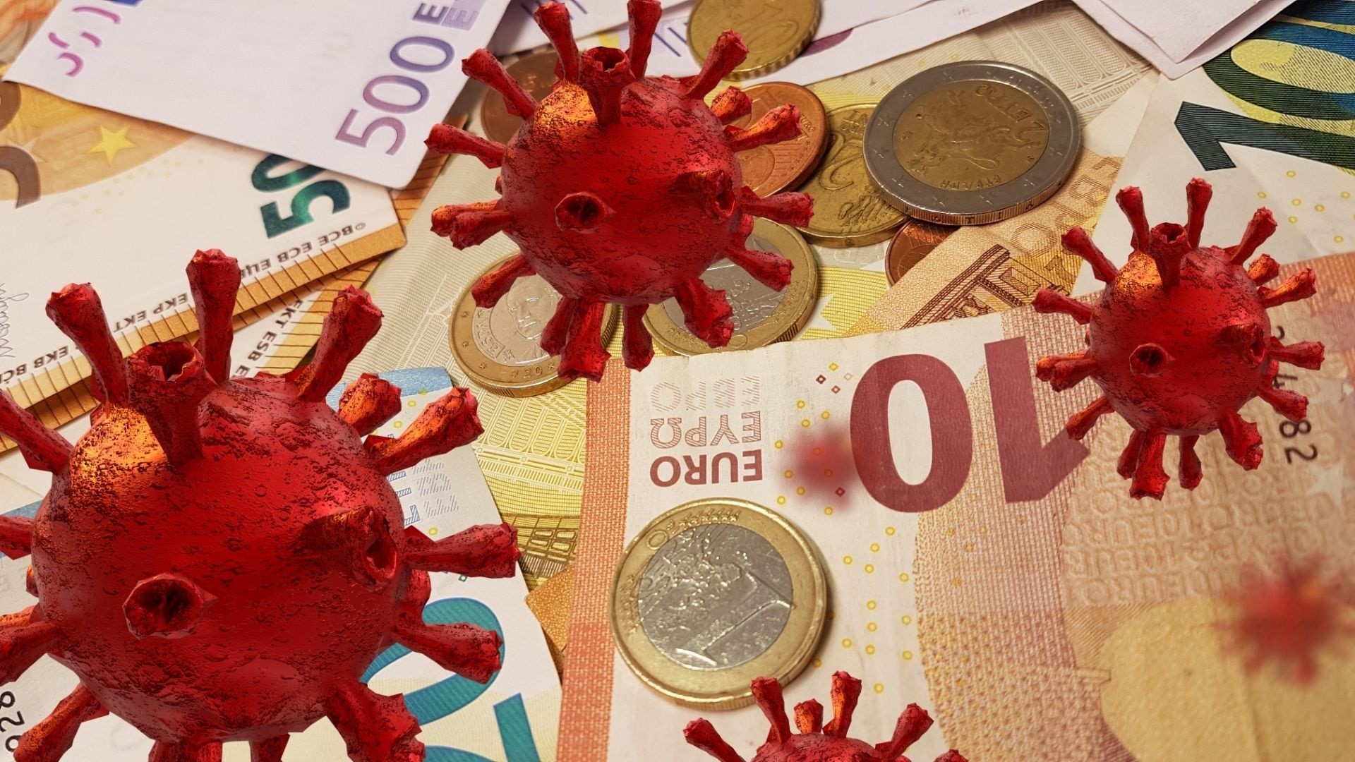  Finanzhilfen, Einnahmen, Ausgaben, Unterstützung - Das Foto zeigt im Hintergrund verschiedene Geldmünzen und schiene. Im Vordergrund ist in rot das Corona-Virus mehrfach abgebildet.