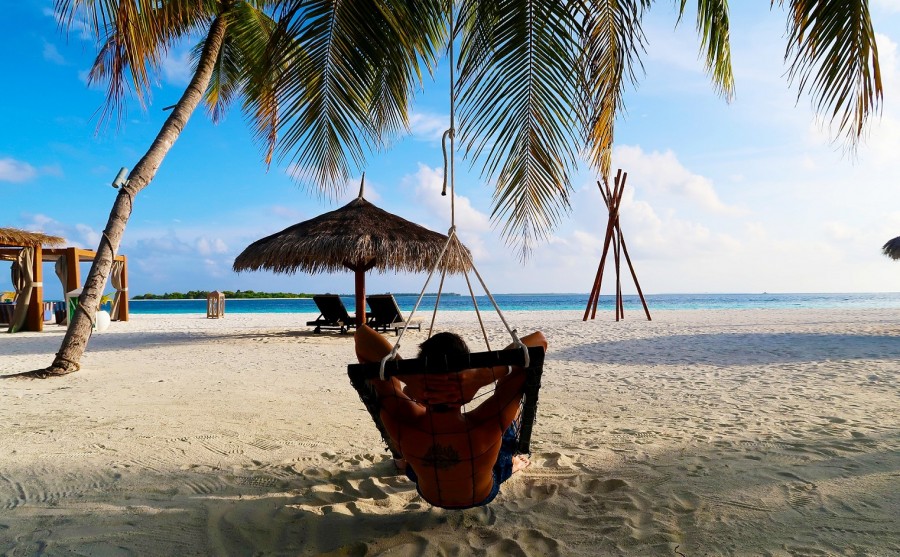 Person in einer Hängematte unter Palmen am Strand. Impfberatung für Auslandsreisen. - Bild von Jose Aitor Pons Buigues auf Pixabay