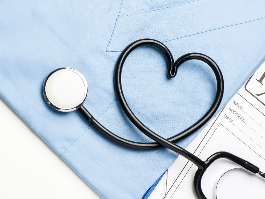 Ein in Herzform gelegtes Stethoskop liegt auf einem Arztkittel. Daneben liegt ein Fragebogen. - Gesundheitsamt - Canva von FabioBalbi