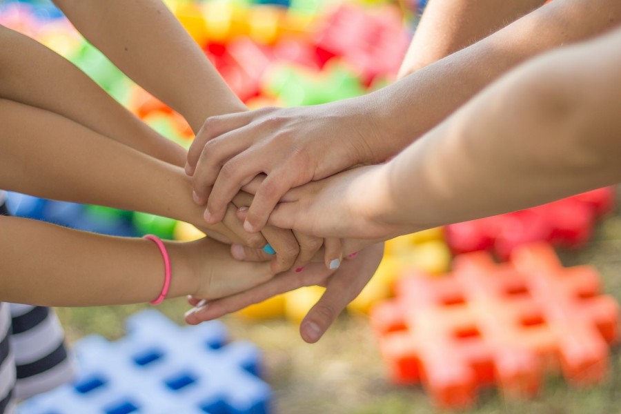 Kinder und Jugendliche vereinen ihre Hände. Symbol für Stadtteilkonferenzen, die auf lokaler Ebene Anstöße zur Entwicklung von positiven Lebensbedingungen von Kindern, Jugendlichen und deren Familien im Stadtteil zu geben. - Pixabay