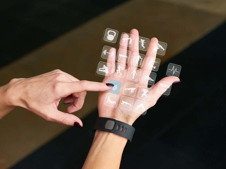 Hände einer Person auf der unterschiedliche sportliche Symbole einer Sport-App zu sehen sind. Digitalisierung im Sport, Fitnesstracker, Sportstudios, Sportvereine - Canva