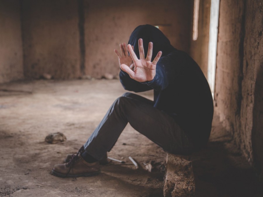 Ein Jugendlicher in einem schwarzen Hoodie mit Kapuze über dem Kopf sitzt in einem verlassenen Gebäude und zeigt eine Abwehrhaltung mit seinen Händen. - Canva - Tinnakorn Jorruang - Gesundheitsamt Steiner