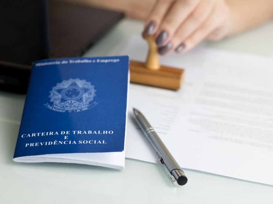 Mitarbeiterin der Ausländerbehörde stempelt einen ausländischen Pass. Informationen zum Aufenthaltsgesetz. Ausländeramt - Canva