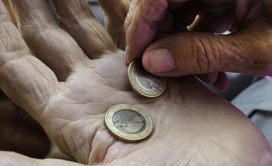 Hände eines alten Menschen, eine Hand dreht zwei 1-Euro-Geldstücke in der anderen Hand um. Senioren, Seniorinnen, Altersarmut, Rente - Pixabay