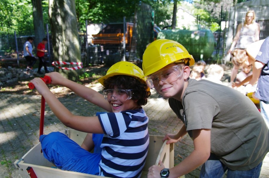 Kinder bei den Ferienspielen mit Bauarbeiter-Helmen. - Amt für Kinder, Jugend und Schule