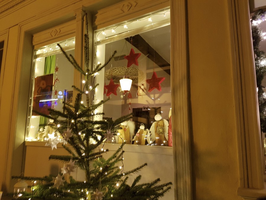 Adventsmarkt Mülheimer Altstadt - Blick in ein adventlich geschmücktes Fenster, davor steht ein beleuchteter Weihnachtsbaum - Daniel Brüning - Foto darf ausschließlich zur Veröffentlichung der Pressemitteilung Mülheimer Weihnachtsmärkte 2023 vom 16.11.2023 honorarfrei genutzt werden.