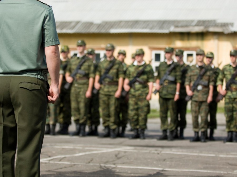 Symbolbild für Bundeswehr, Soldaten stehen in einer Reihe, vorne im Bild ist der Rücken einer vorgesetzten Person zu sehen. - Canva