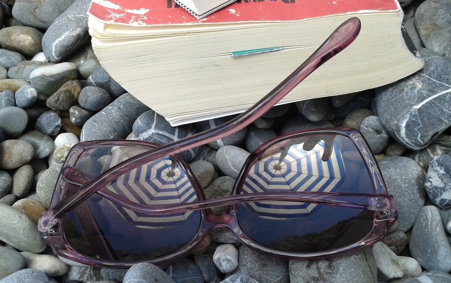 Buch und Sonnenbrille auf Steinen. Symbol für Urlaub. - Pixabay