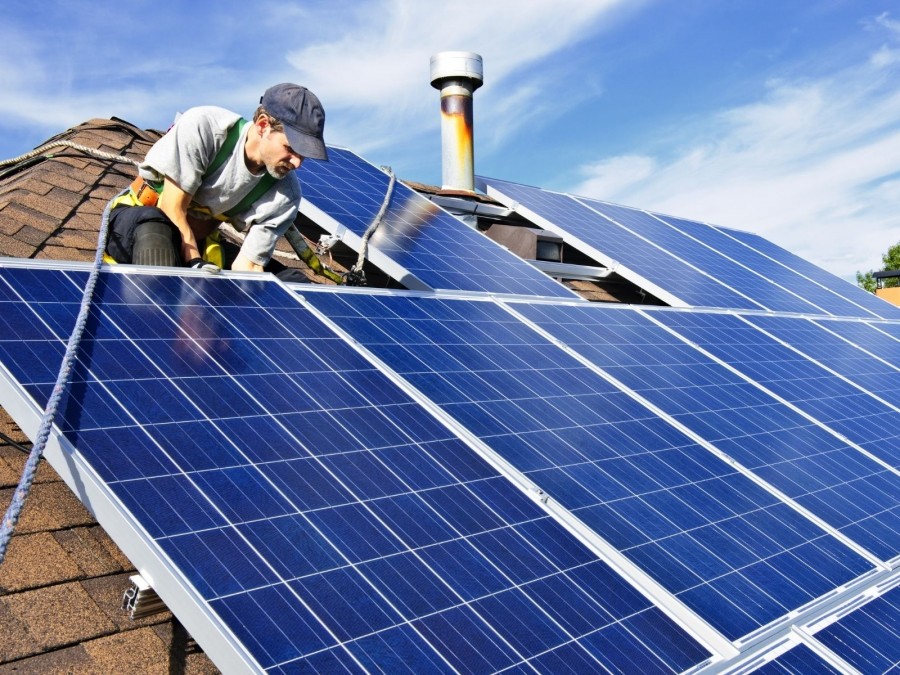 Arbeiter an einem Sicherheitsseil befestigt montiert Teile eines Solardaches. Energiewende, Umweltschutz, Naturschutz, natürliche Energiequellen, Sanierung, - Canva