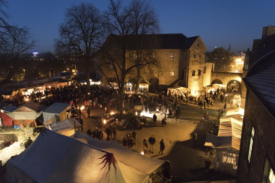 Broicher Schlossweihnacht: Das Foto zeigt eine Luftaufnahme von der Mittelalterveranstaltung im Schlossinnenhof am Abend - PR-Fotografie Köhring