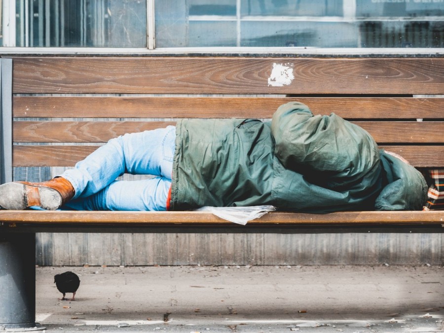 Ein Obdachloser übernachtet auf einer Parkbank in der Innenstadt. - Online Redaktion - Referat I - Canva - Srdjanns74