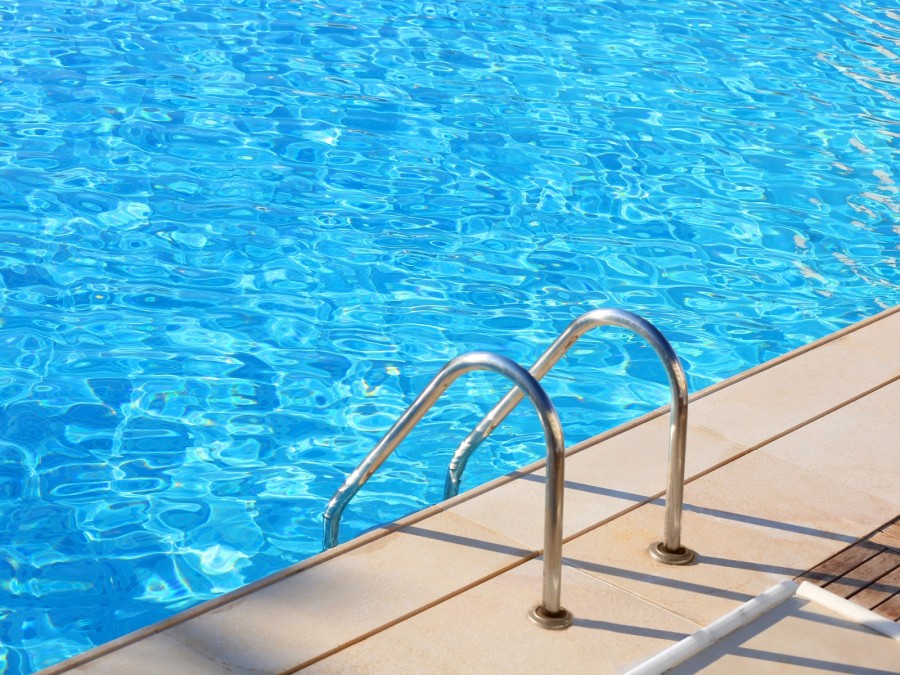 Schwimmen, Schwimmbad, Freibad: Foto vom Beckenrand eines Schwimmbads mit Ausstieg und Wasserausschnitt - Canva